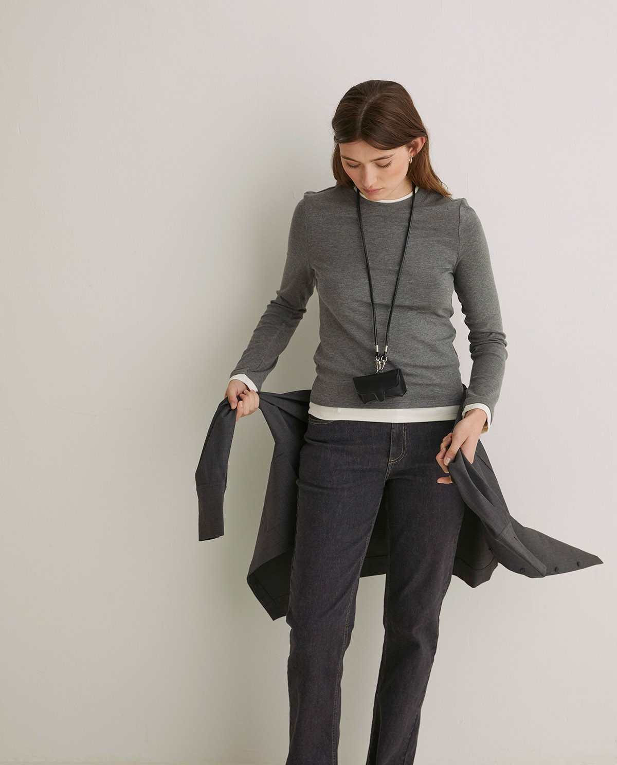 Black rigid mini wallet by Yerse with snap-button closure and removable neck strap