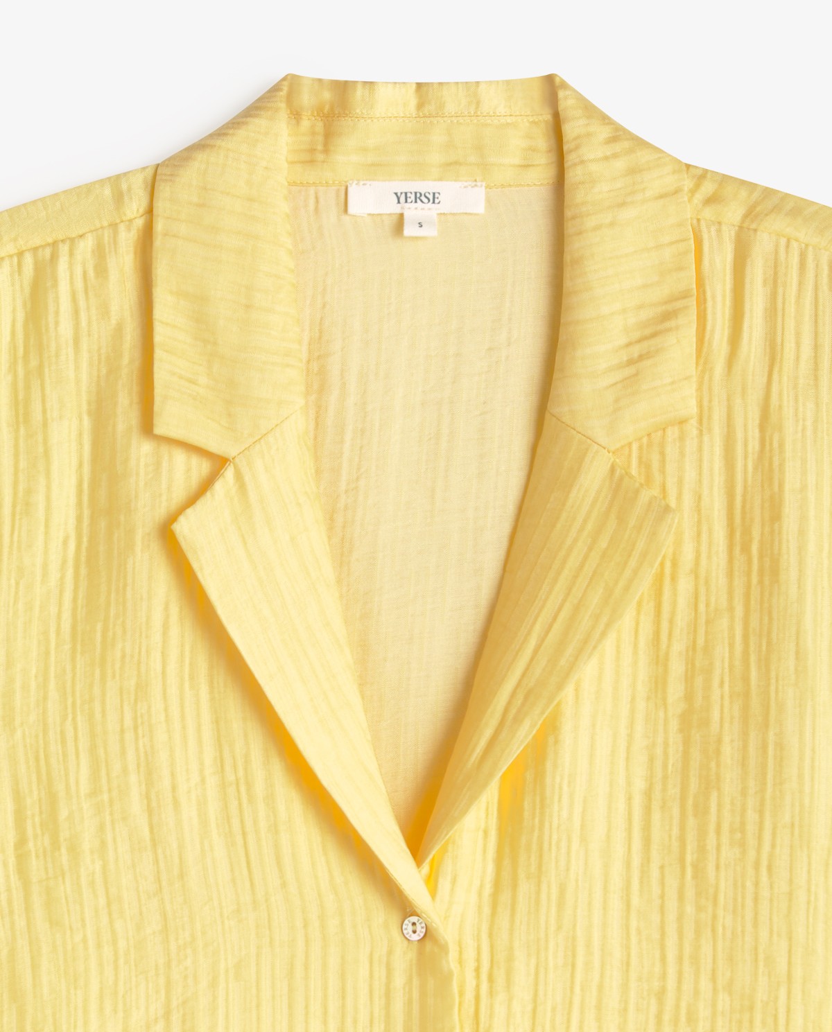 Camisa manga corta cuello solapa en color amarillo pastel, vista frontal con detalle del tejido 6