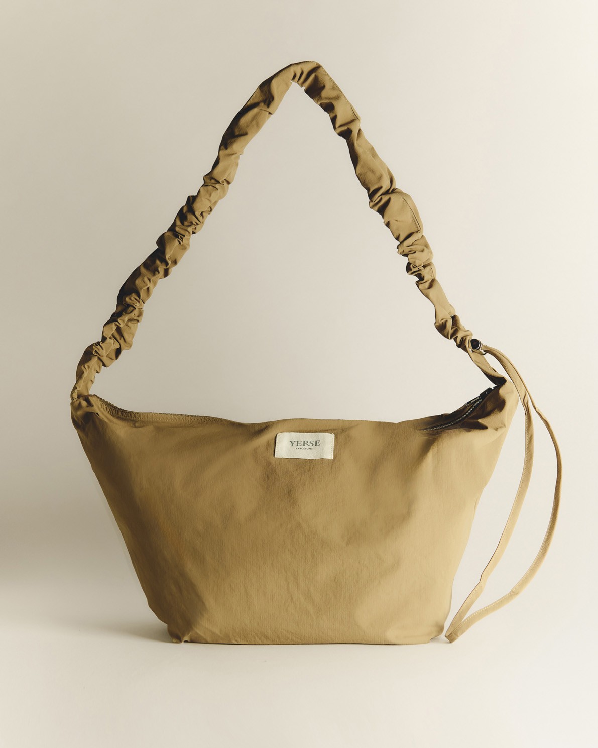 Bolso estilo riñonera con cremallera en color caqui, vista frontal con detalle del tejido