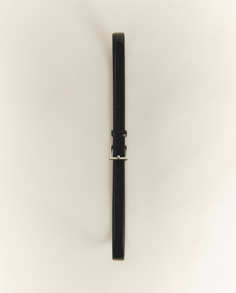 Cinturón fino con hebilla plateada en color negro, vista frontal con detalle del tejido